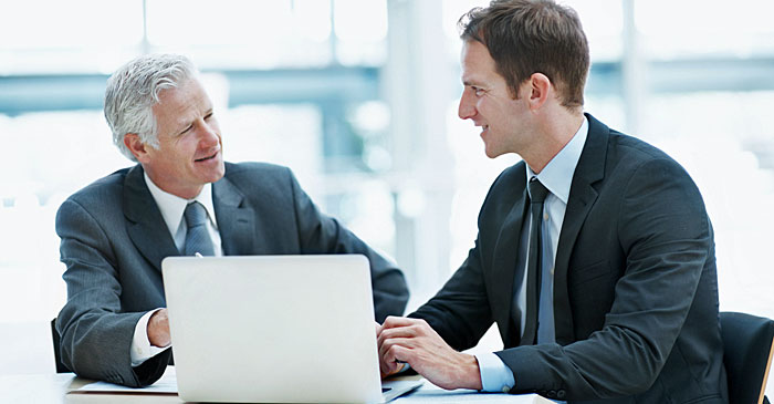 Zwei Wirtschaftsprüfer unterhalten sich über ein Dokument an einem Laptop